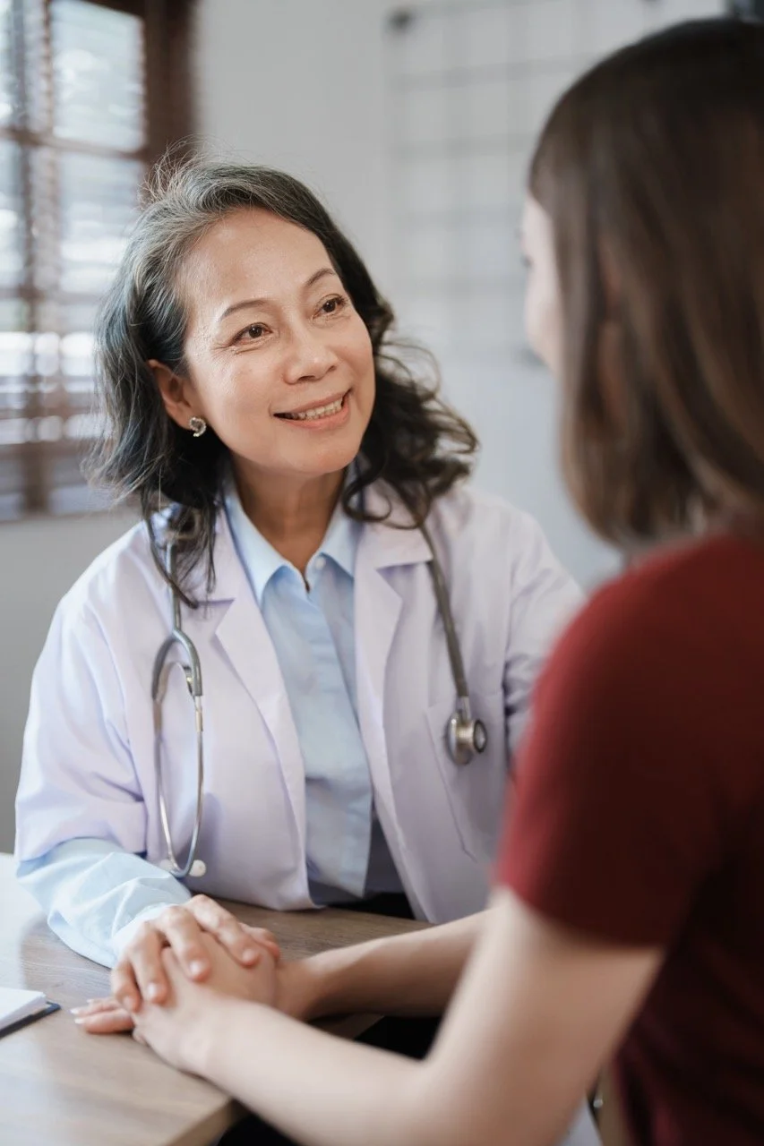 A doctor smiling while talking to a female patient in a consultation.