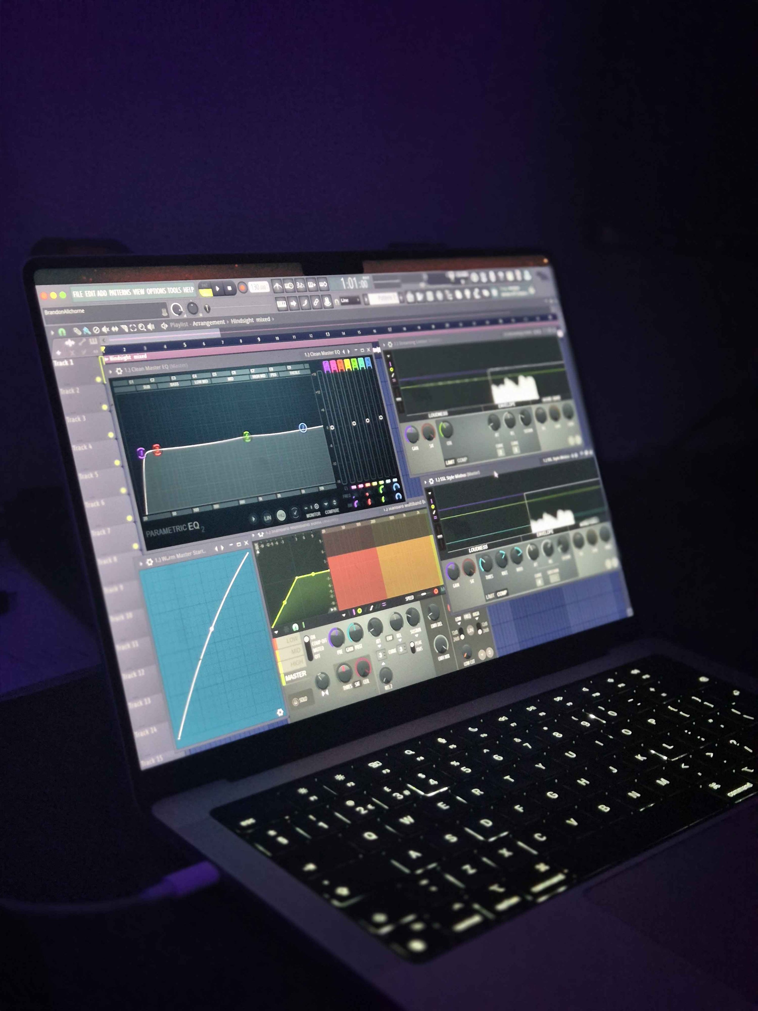 Laptop displaying digital audio workstation with music mixing and editing software.