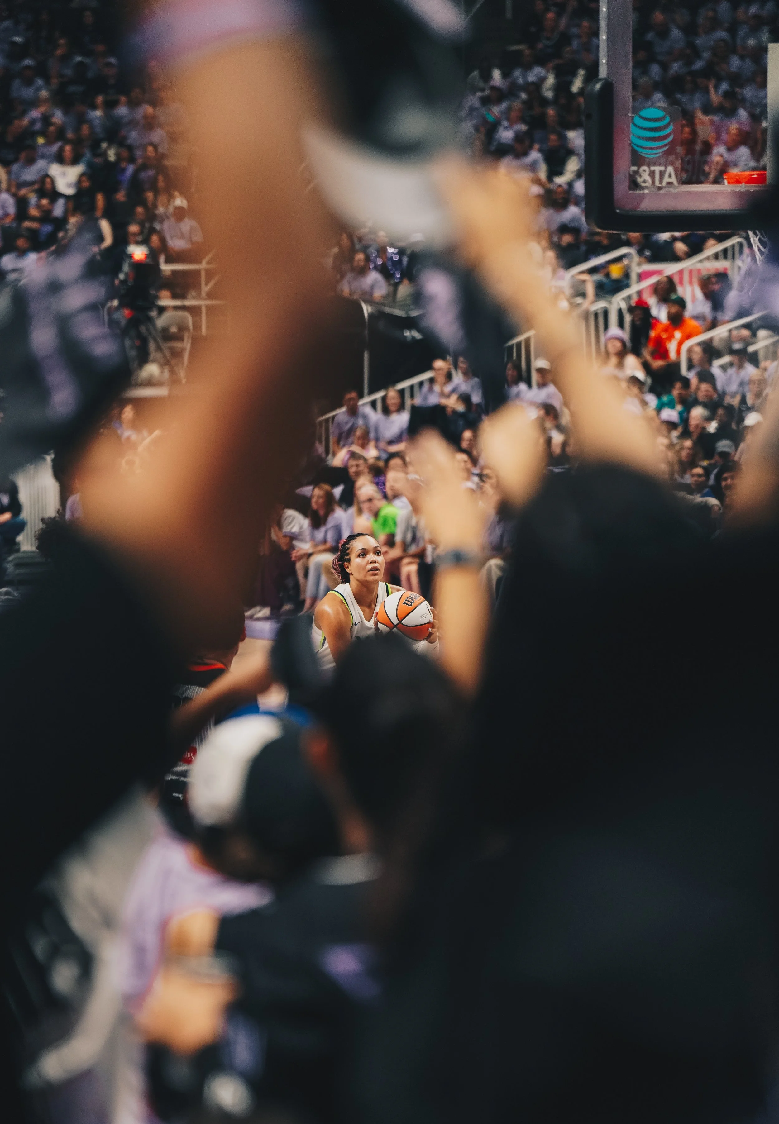 A female basketball player preparing to shoot free throw on a crowded indoor court with spectators in the background.