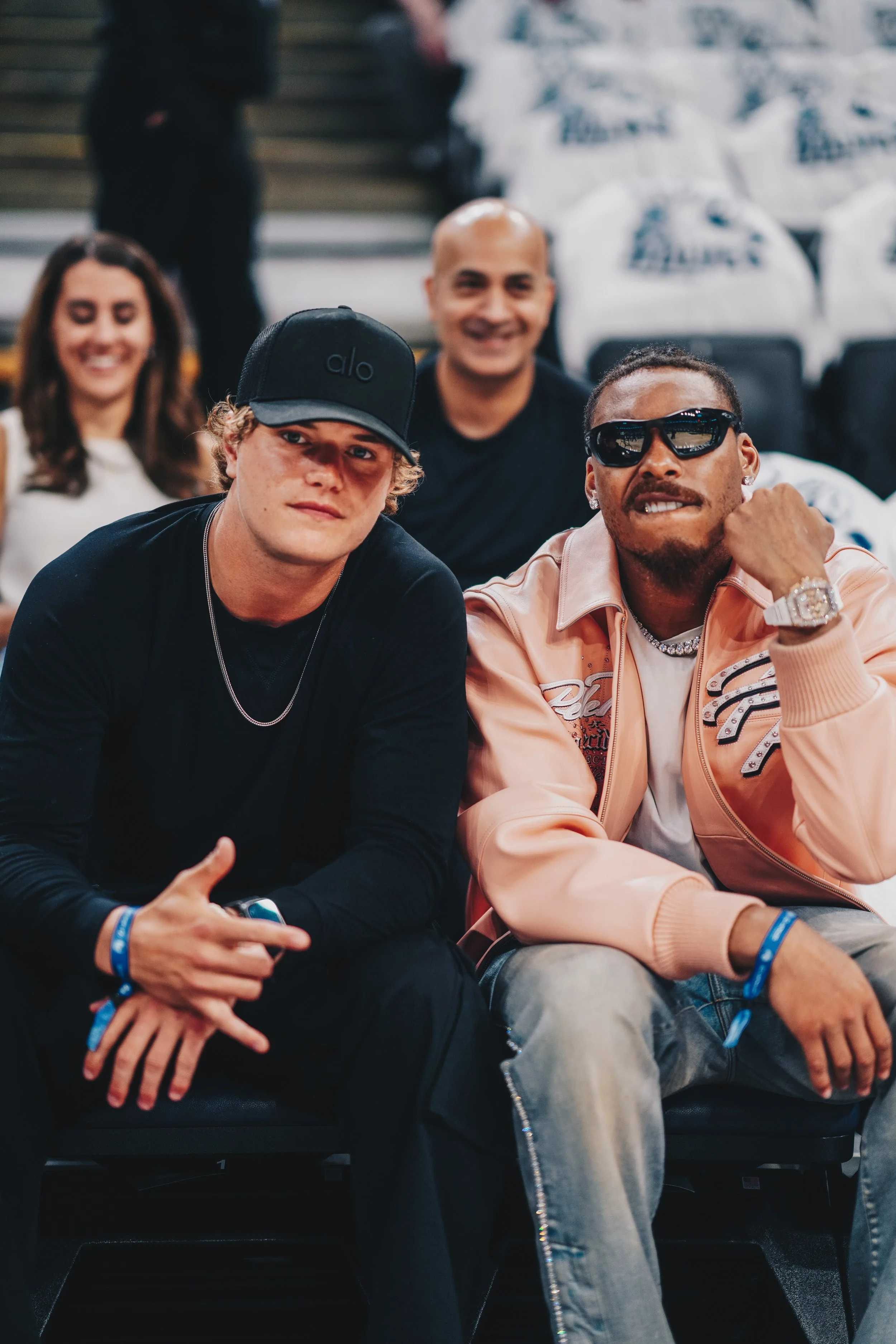 Group of four smiling people sitting in seats, two young men in the front and two women in the back, at an event.