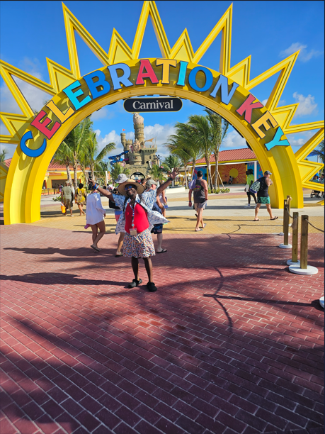 People entering the Coney Island amusement park through a large, colorful archway that says "Celebration Key" with a carnival in the background.