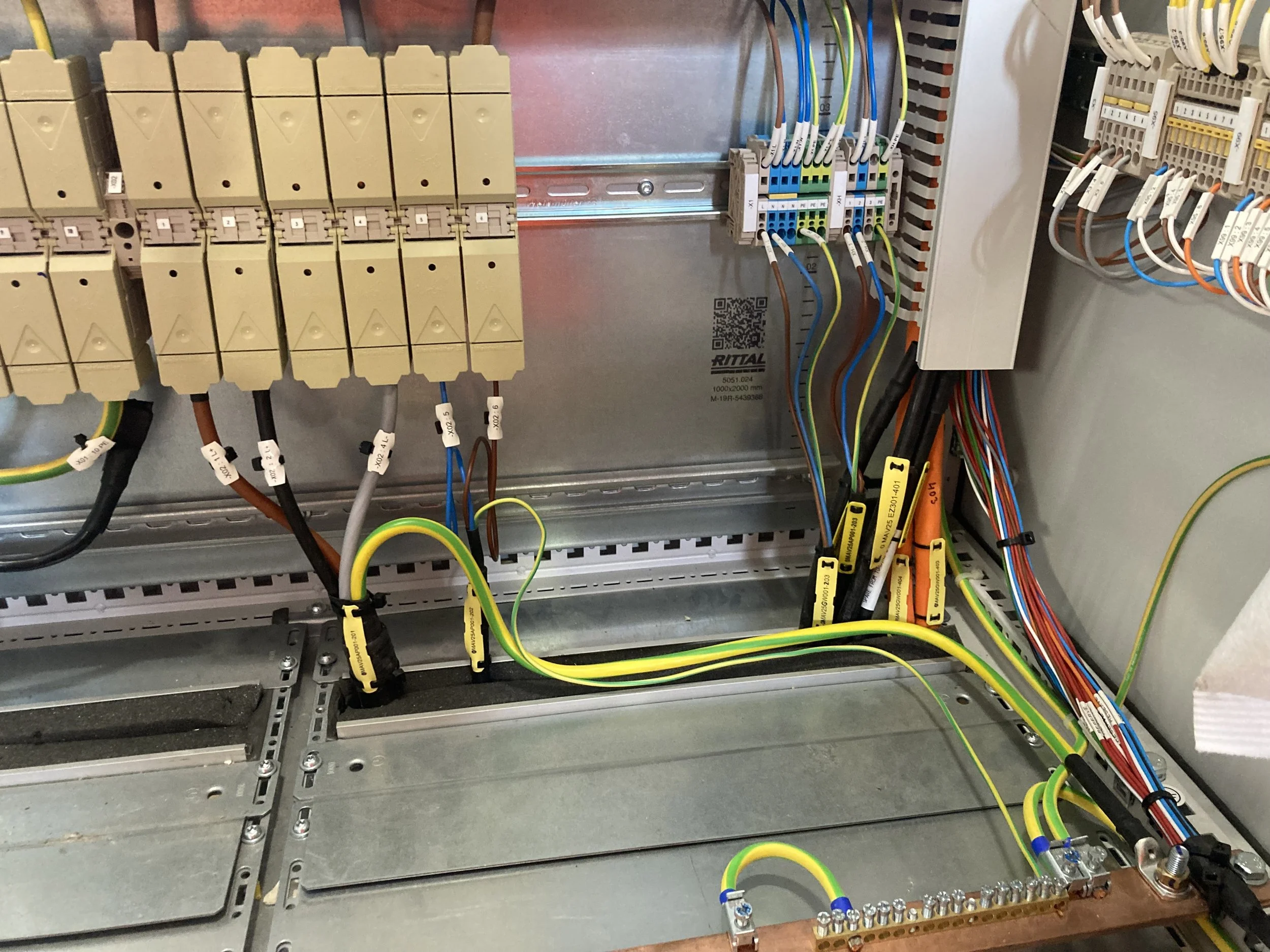 An electrical panel with various colored wires, terminal blocks, and connectors arranged inside a metal enclosure.