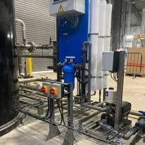 Industrial machinery and piping in a factory setting, featuring control panels and equipment.