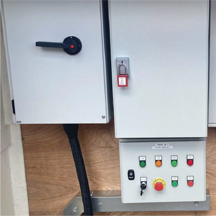 Electrical panel with a switch, lock, and control buttons on a wooden wall.