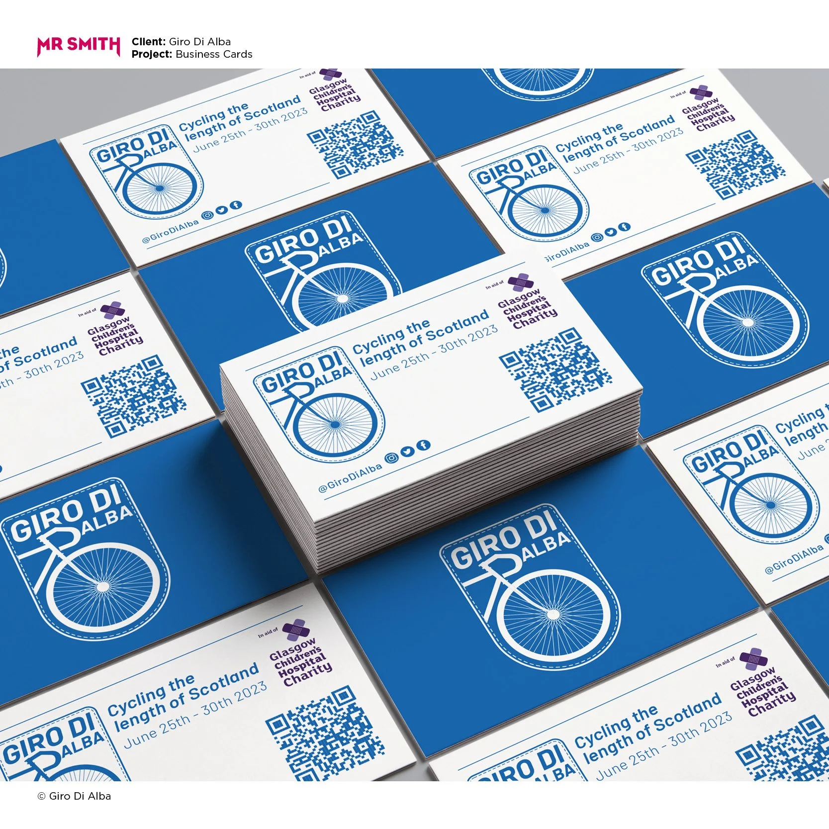 Stacks of business cards for the Giro di Alba cycling event, featuring a blue and white design with a bicycle wheel illustration, event details, a QR code, and social media icons.