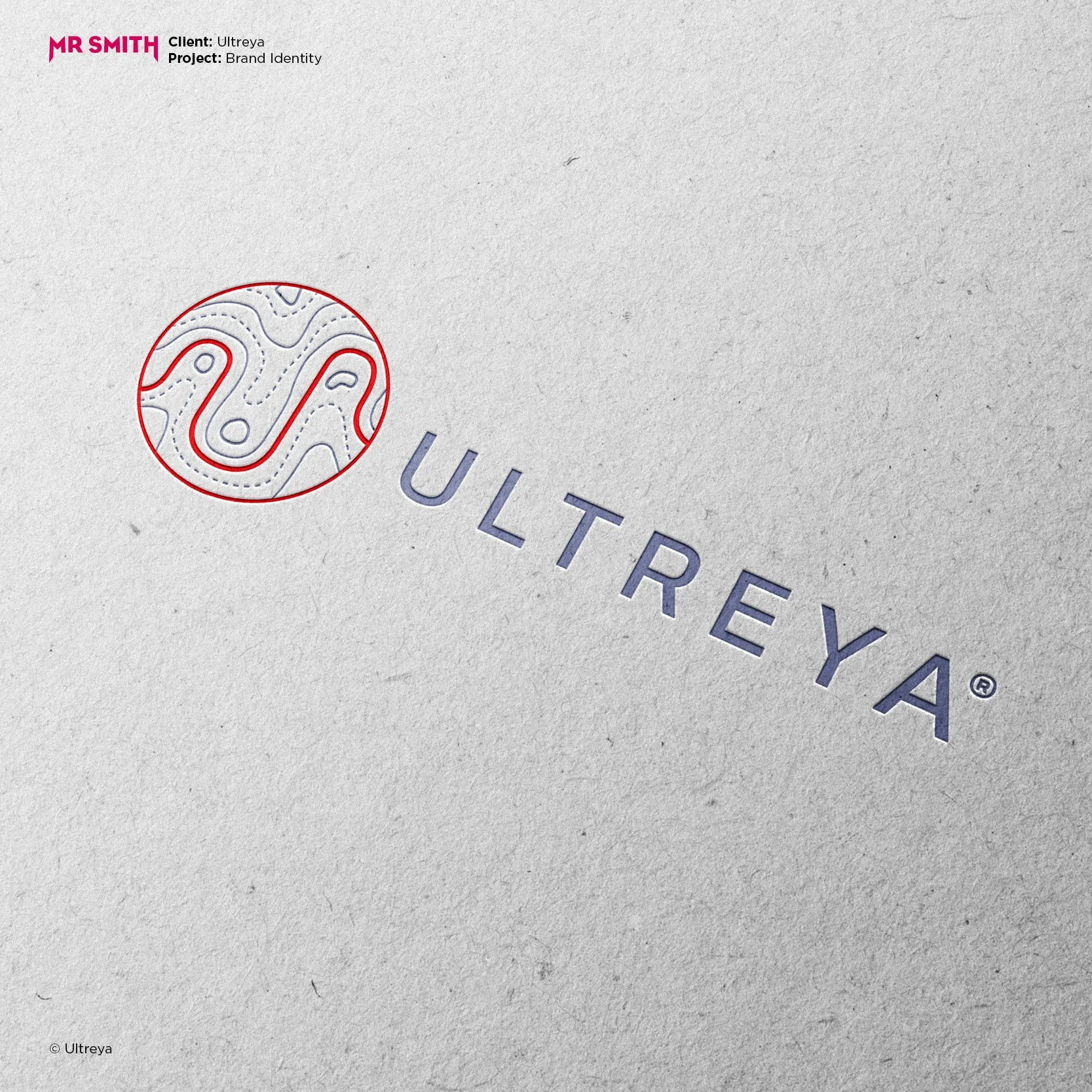 Close-up of a textured paper with a circular logo containing a stylized map design in red and white, and partially visible text 'ULTRREY' in purple.