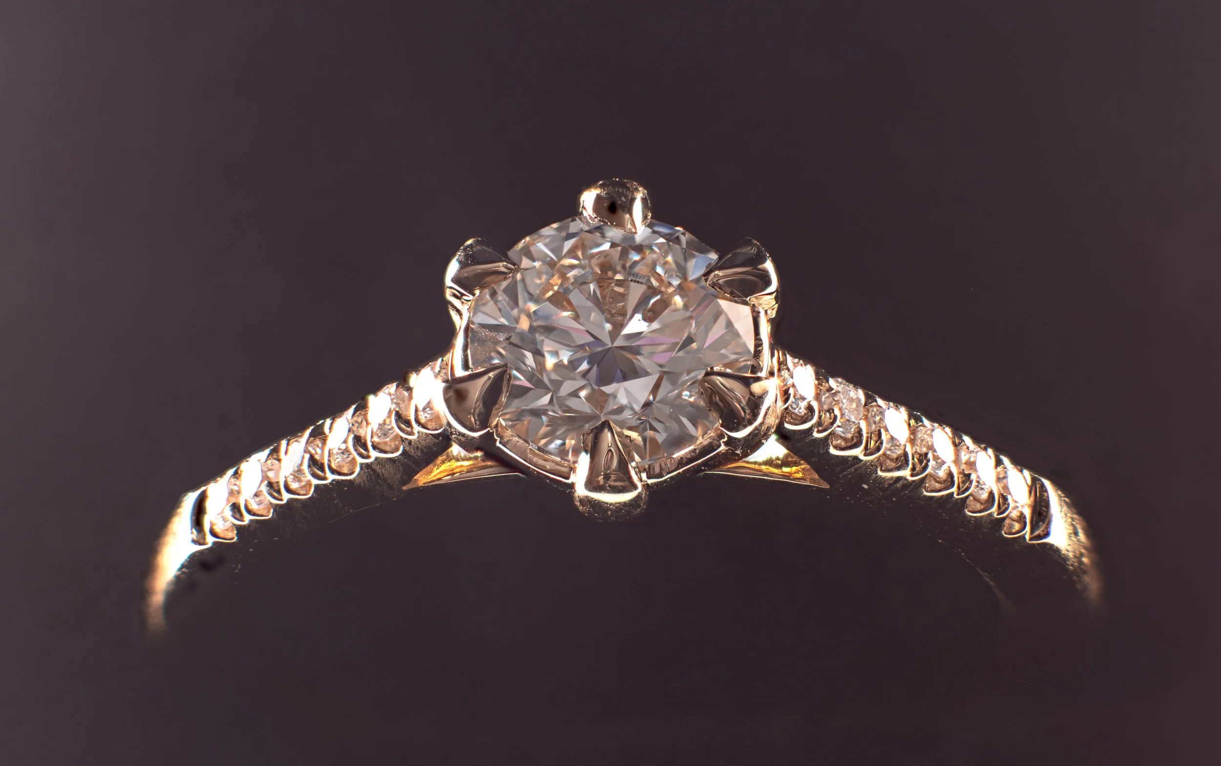 Close-up of a gold diamond engagement ring with a large solitaire and small diamonds along the band