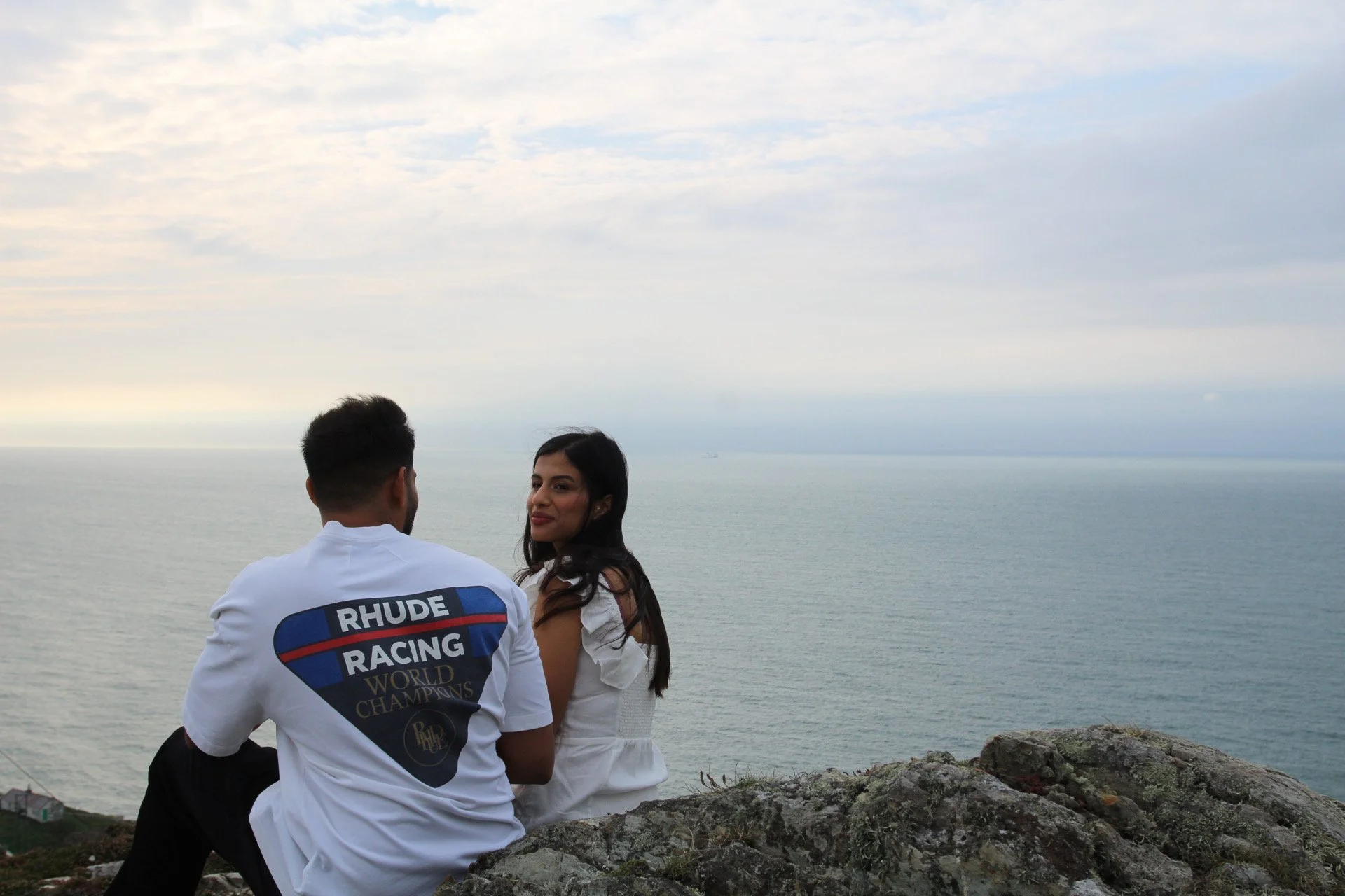 A couple sitting on rocks looking out to sea