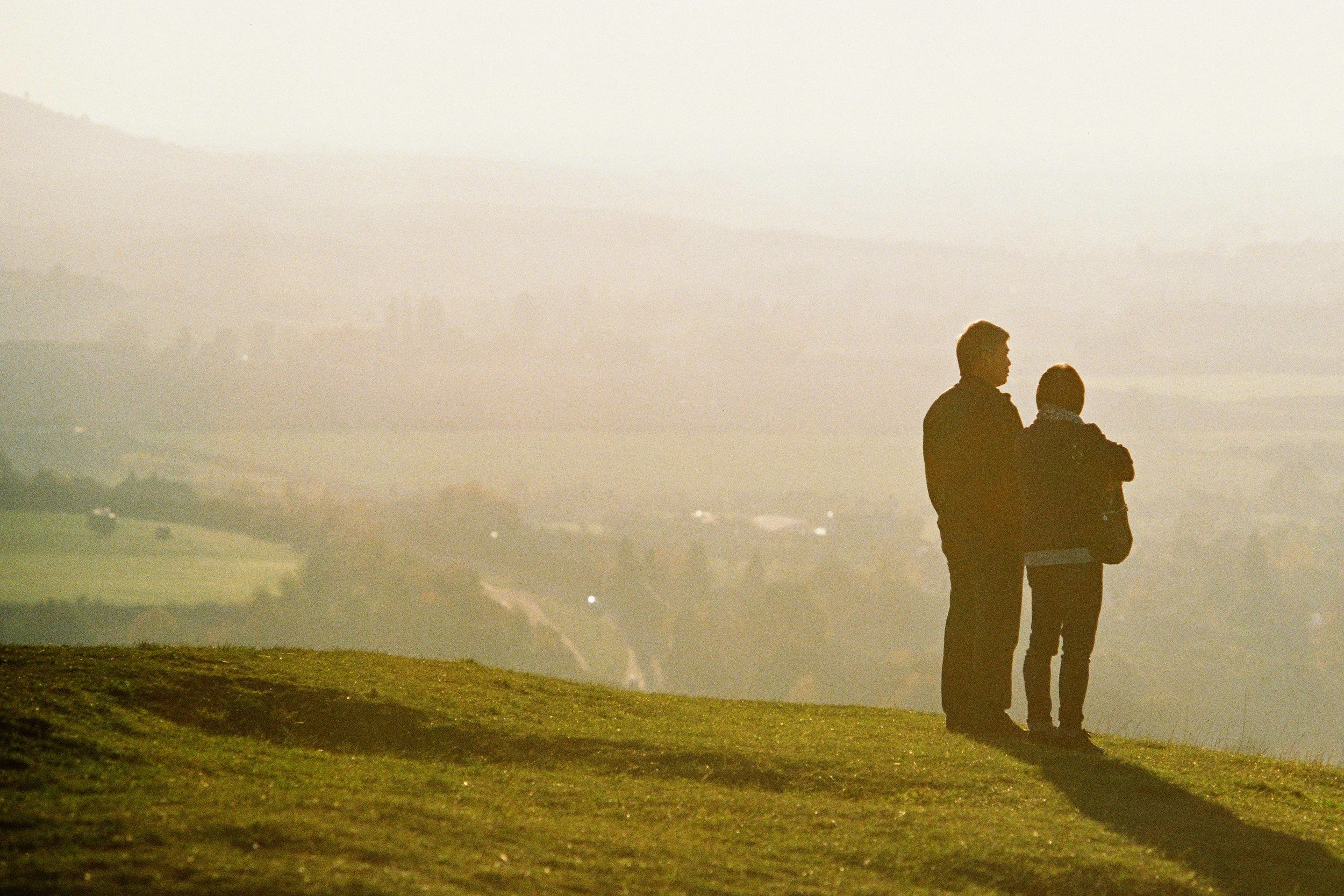 Couple embracing in open countryside under a soft sky