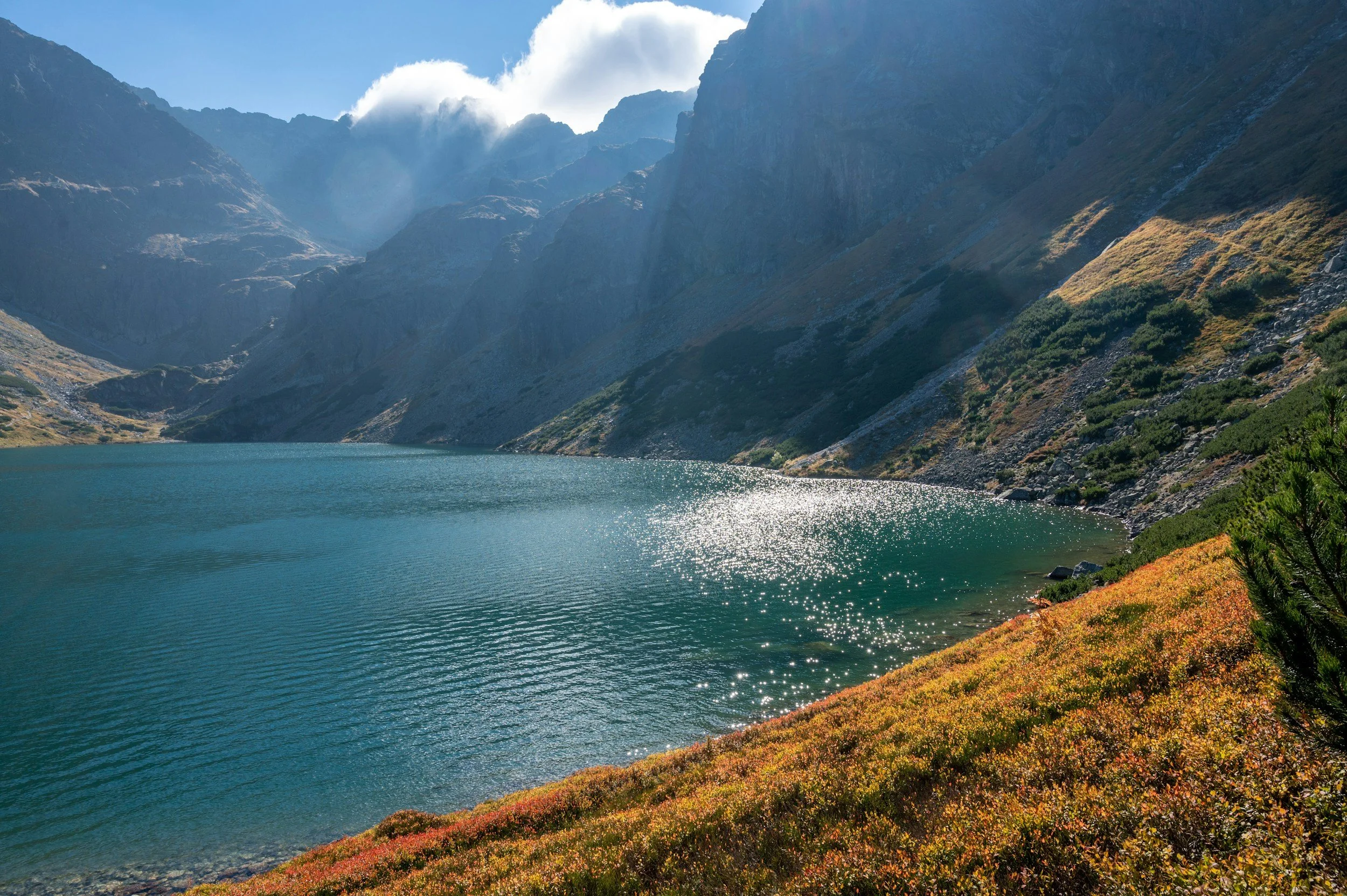 Walking trail leading to a mountain lake surrounded by peaks