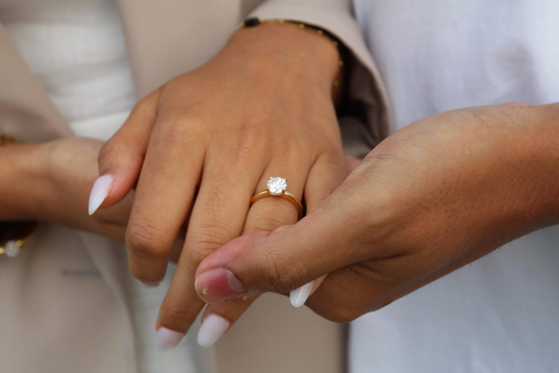 Close-up of a hand with a diamond engagement ring resting in a partner's hand