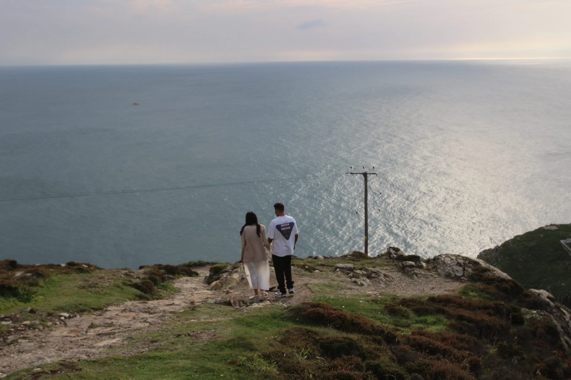 A couple standing together on a clifftop overlooking the sea