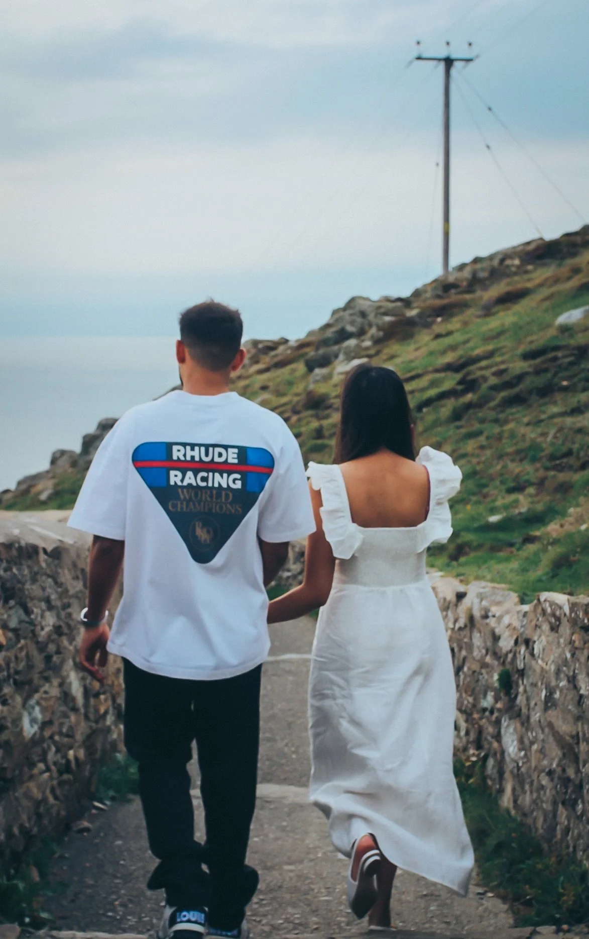 A couple walking hand in hand along a country lane, seen from behind