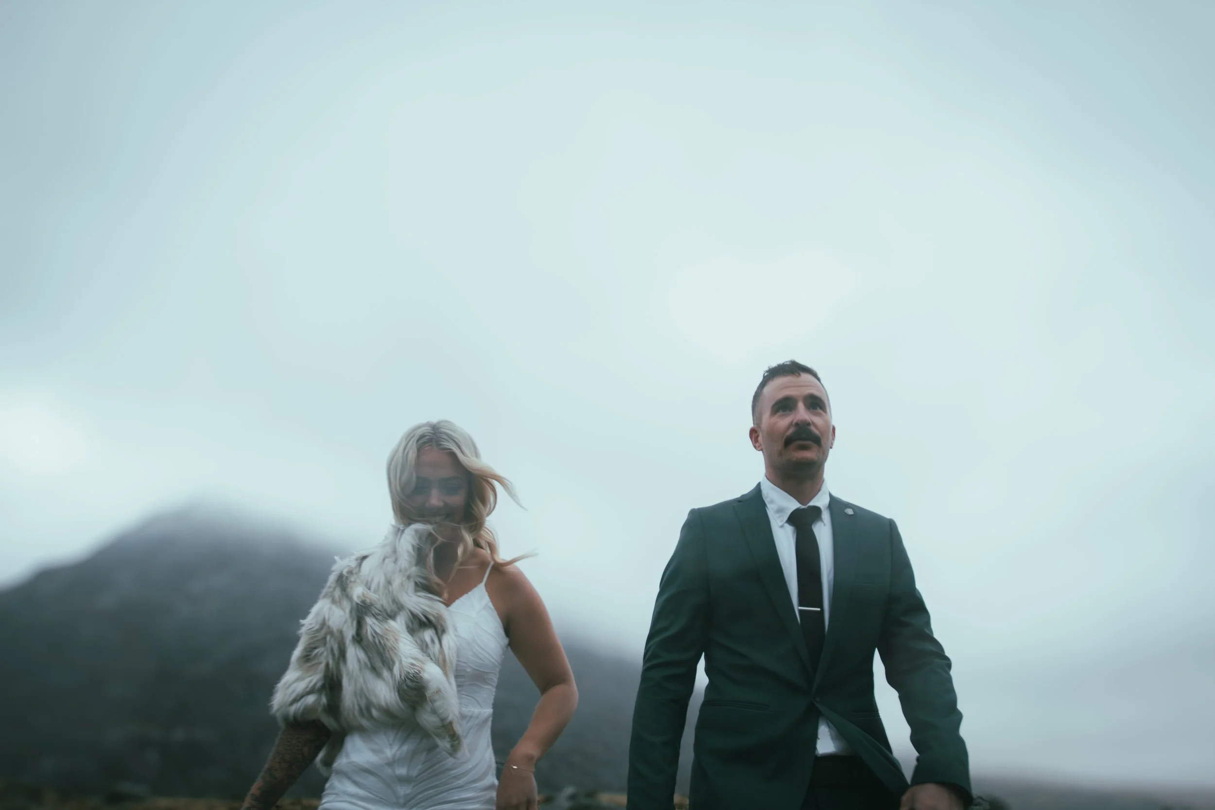 A couple walking together on a misty, windswept hillside