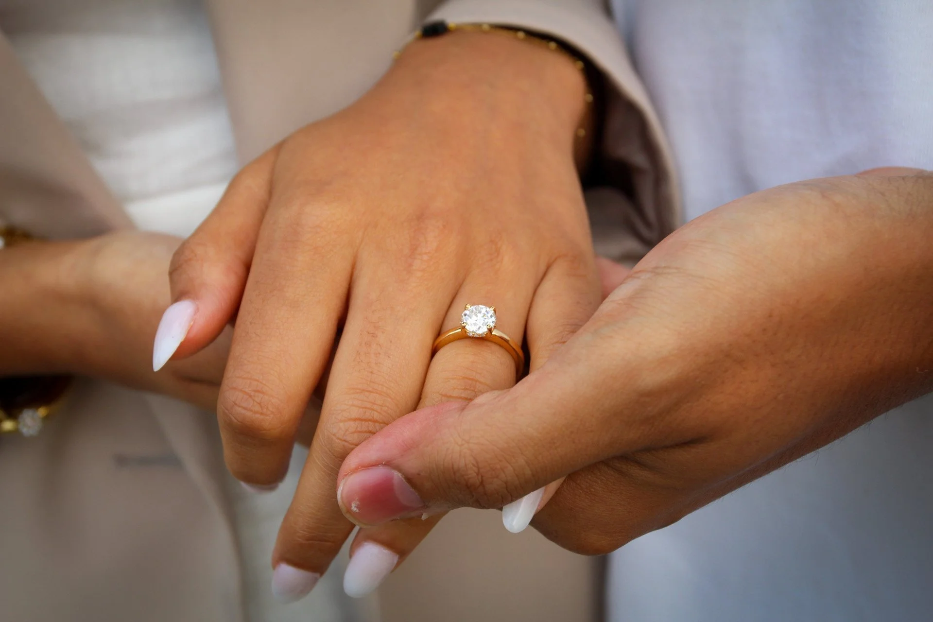 Close-up of a hand with a diamond engagement ring resting in a partner's hand