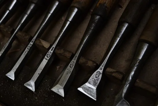 Several chisels arranged in a row on a workbench.
