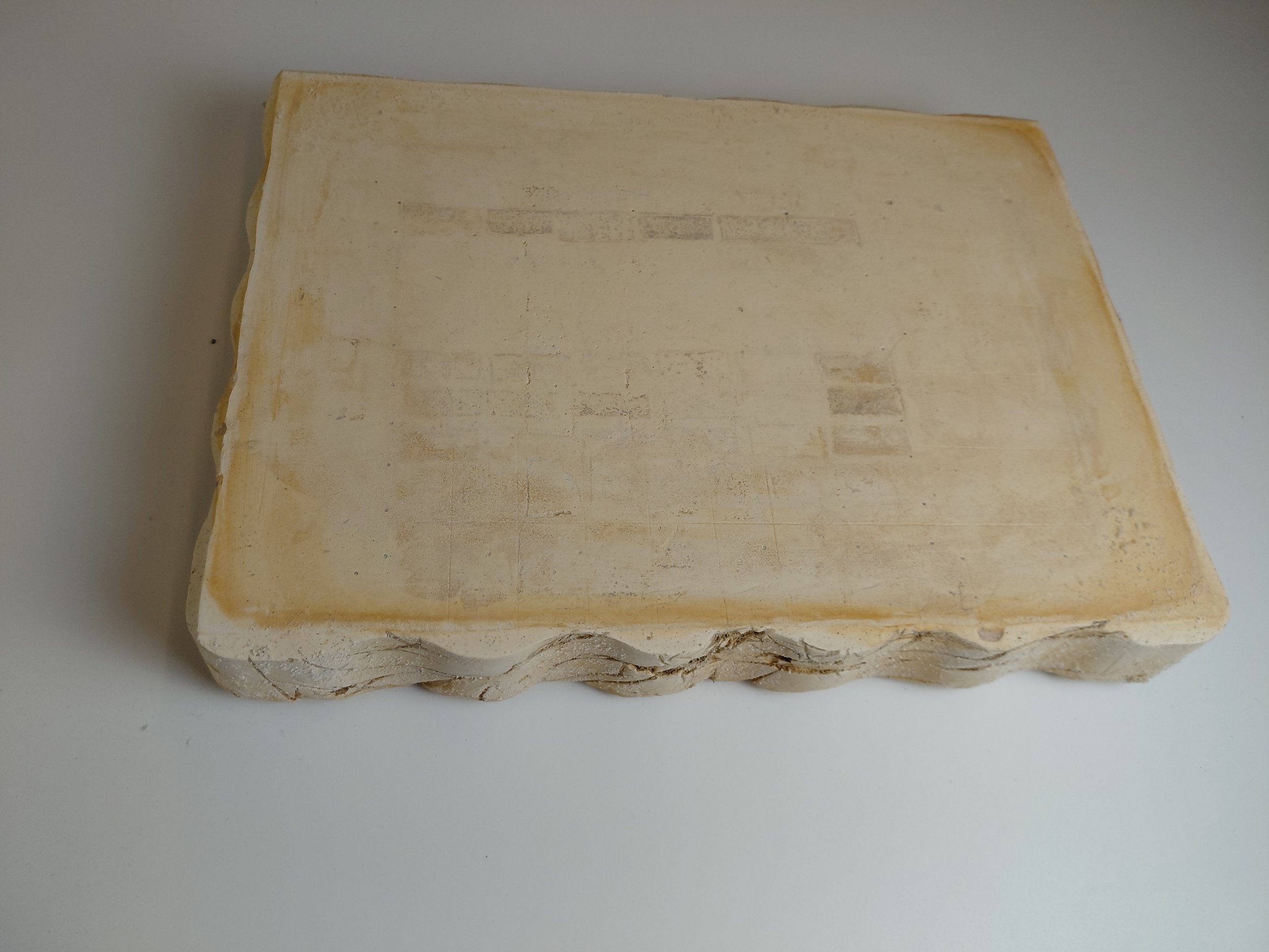 A rectangular plaster block for slab construction, showing corrosion from successive paper glaze exposure
