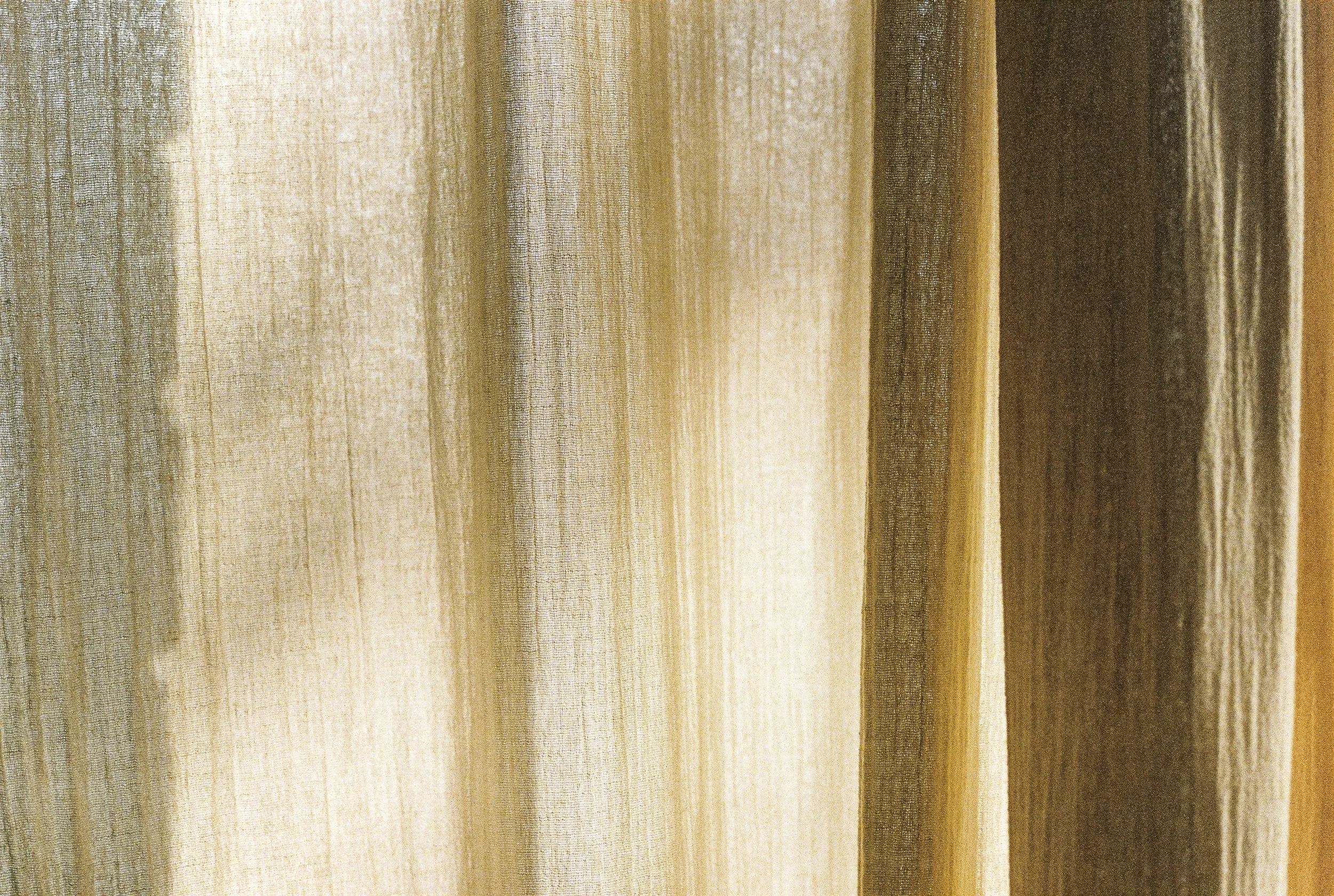 Close-up of beige, cream, and brown fabric curtains with vertical folds.