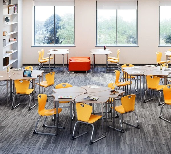 Classroom or meeting room with yellow chairs, round tables, large windows, and an orange ottoman in the center.