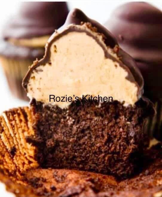Close-up of a chocolate cupcake with white vanilla ice cream inside, topped with a chocolate-covered cookie on a white surface.