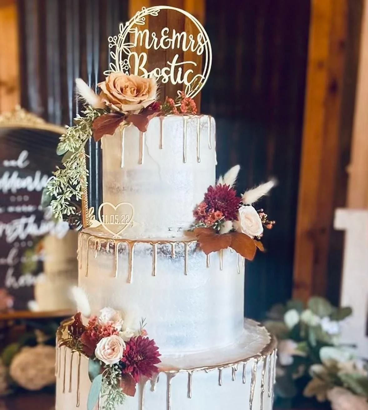 A three-tiered wedding cake decorated with flowers and a top topper that reads 'Mr & Mrs. Bostic'.