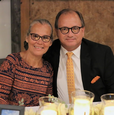 An older woman and man sitting together at a dinner table, smiling, with lit candles in front of them.