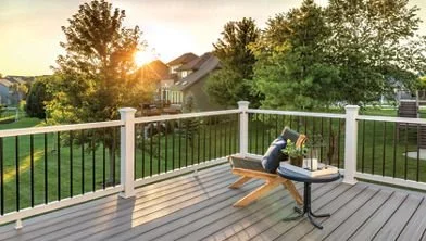 Outdoor deck with railing, bench, and table at sunset