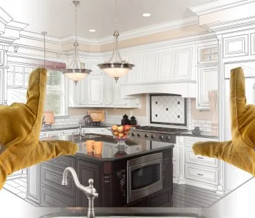 Hands wearing work gloves framing a kitchen design with half photo-realistic and half blueprint view; featuring a modern kitchen with an island, pendant lighting, and stainless steel appliances.