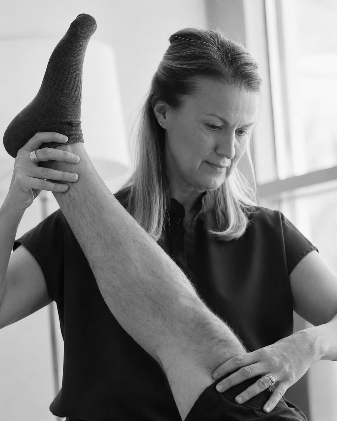 A woman is receiving physical therapy or stretch therapy from a therapist, focusing on the woman's arm and side, in a clinical or therapy setting.