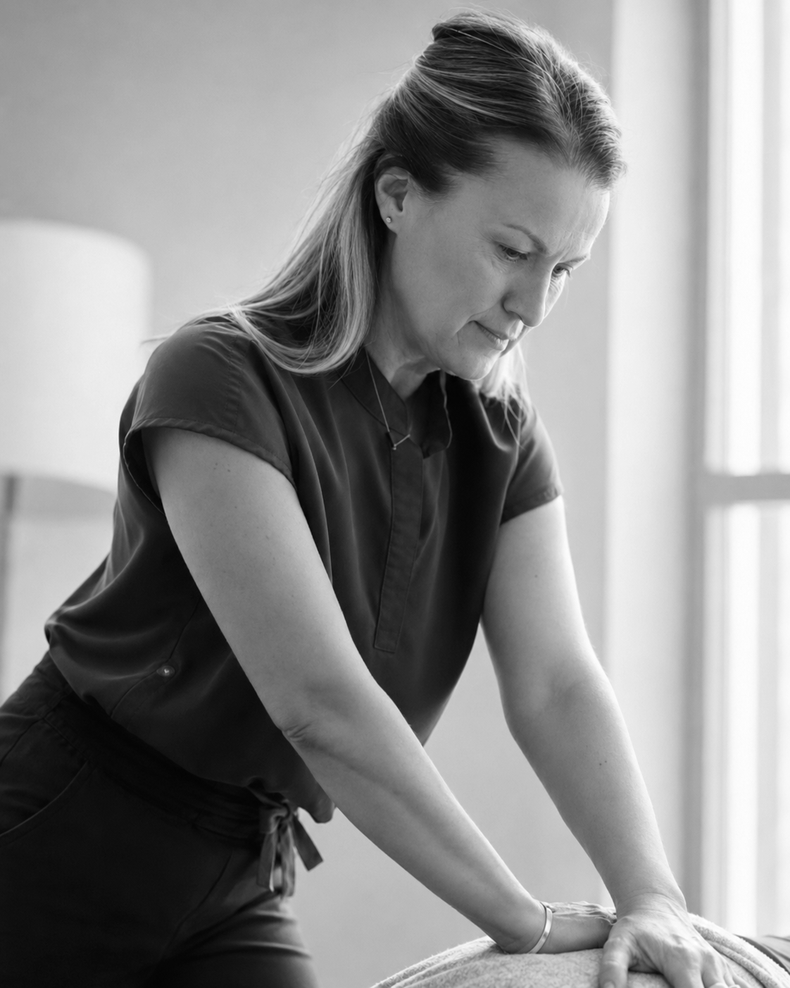 A woman giving a massage, focused and in a relaxing setting.