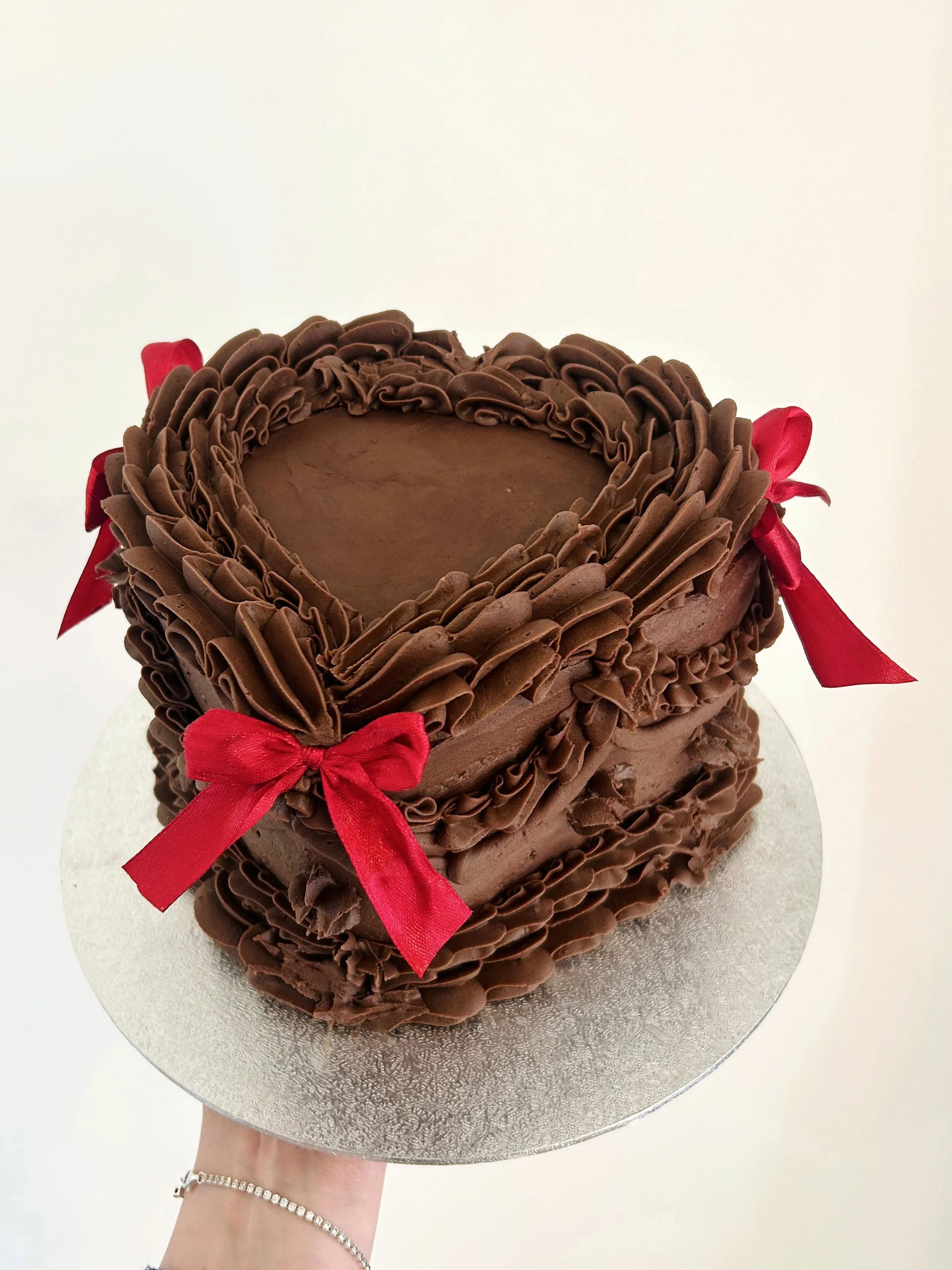 Heart-shaped chocolate buttercream cake with red bows