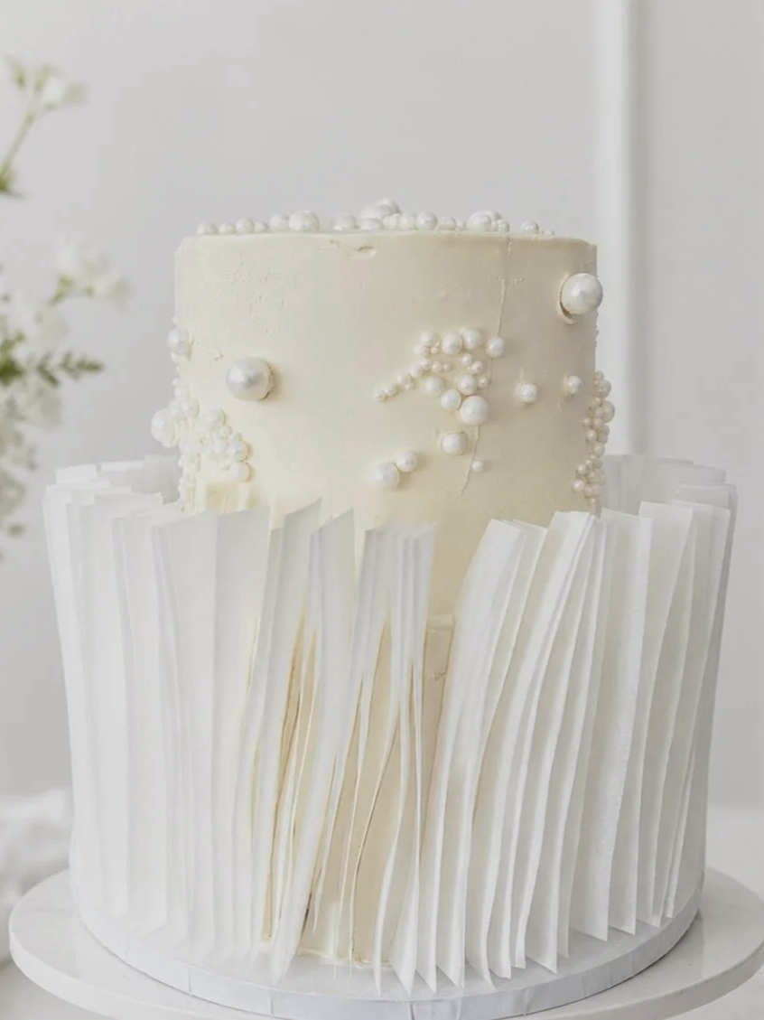 Two-tier white wedding cake with edible pearls and wafer paper