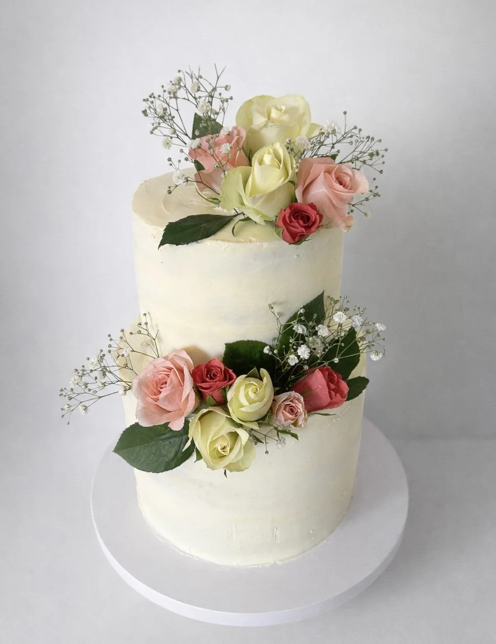 Two-tier white buttercream wedding cake with fresh roses