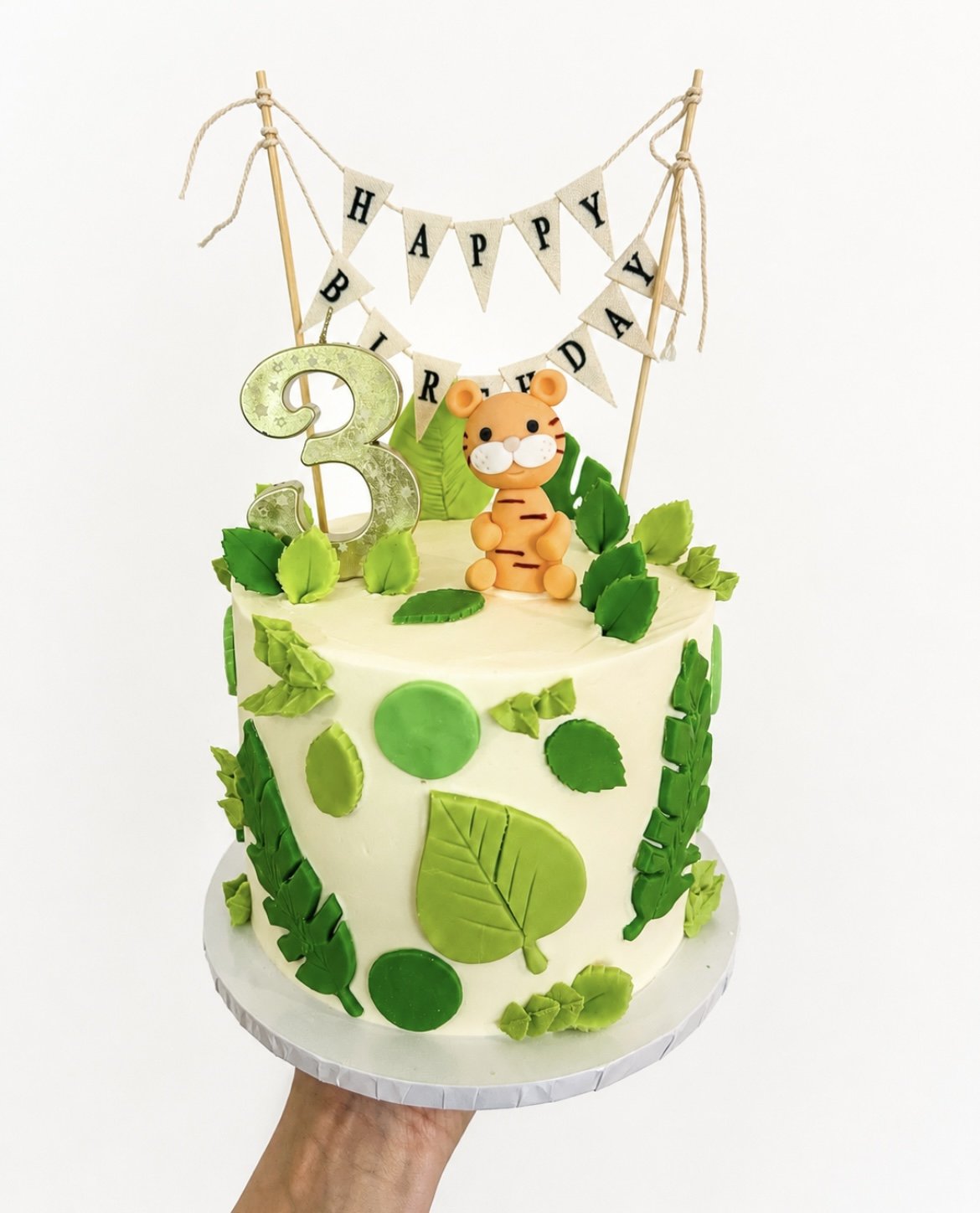 Jungle-themed third birthday cake with a tiger topper