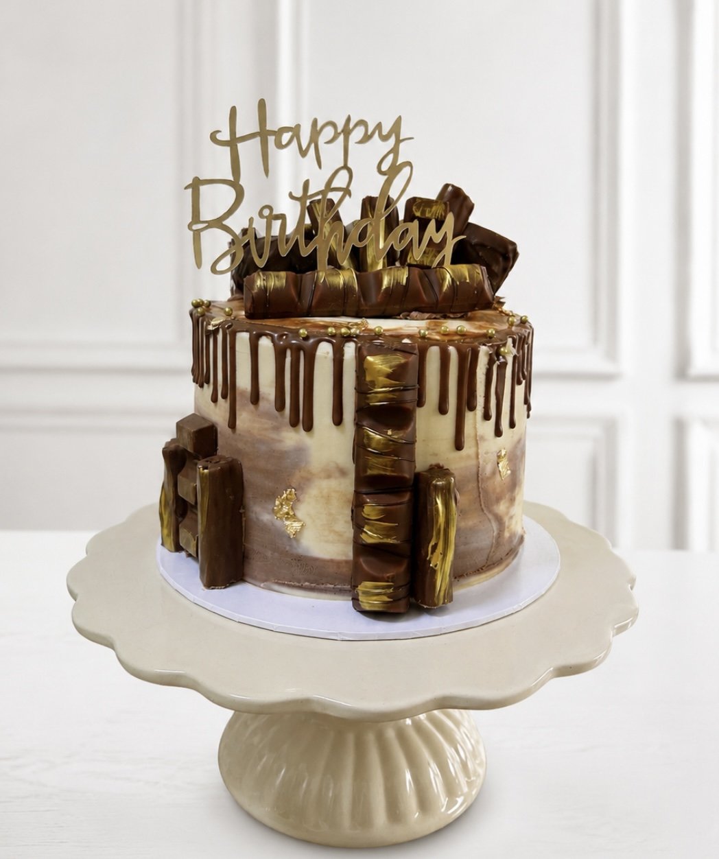 Chocolate drip birthday cake with chocolate bars and a gold Happy Birthday topper