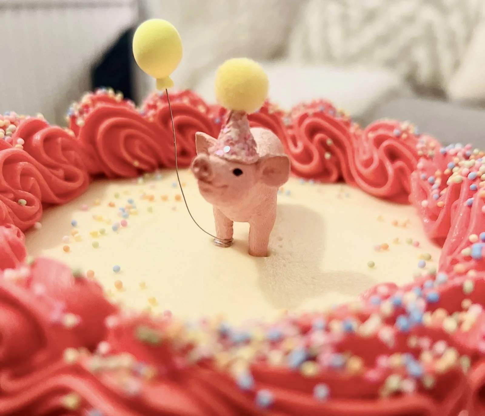 Celebration cake with a pig topper, red piping and sprinkles