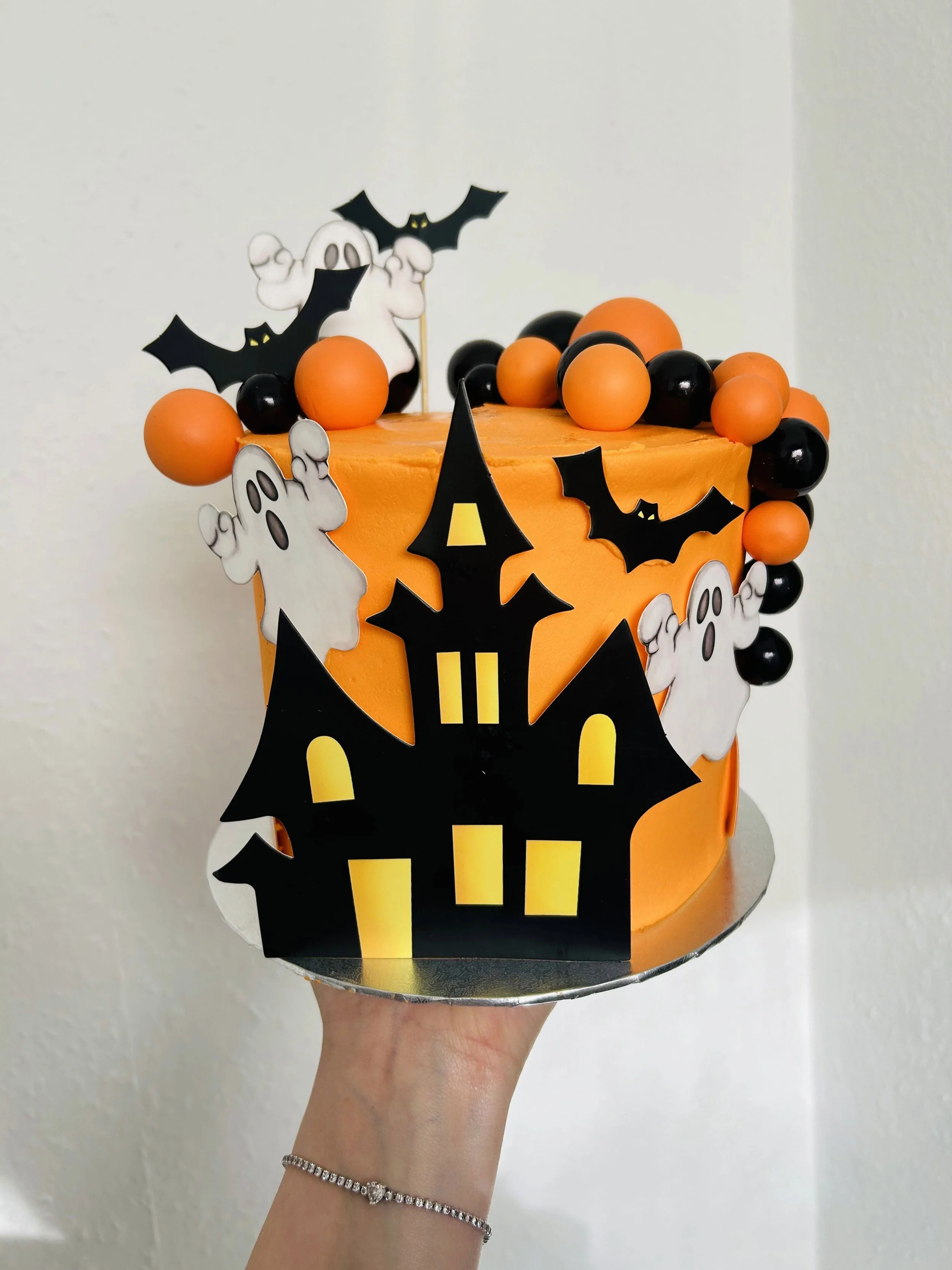 Orange Halloween cake with a haunted house, ghosts and bats
