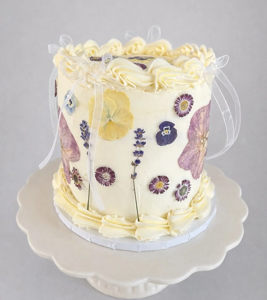 Buttercream cake with pressed flowers and ribbons