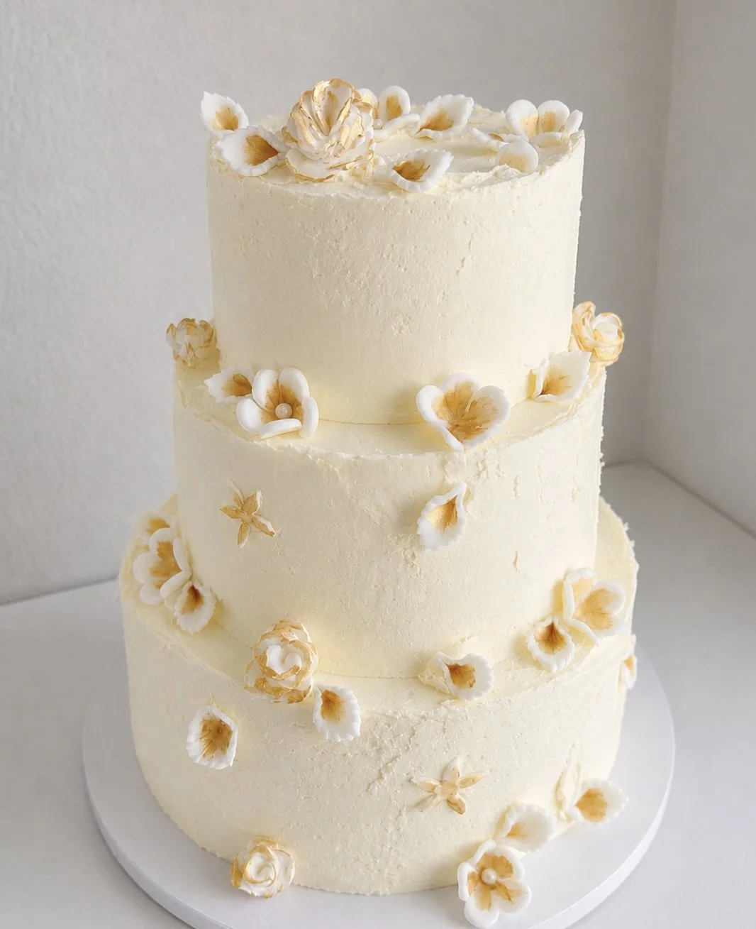 Three-tier buttercream wedding cake with fondant flowers