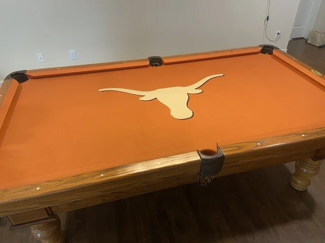 Pool table with a Longhorn steer logo in the center.