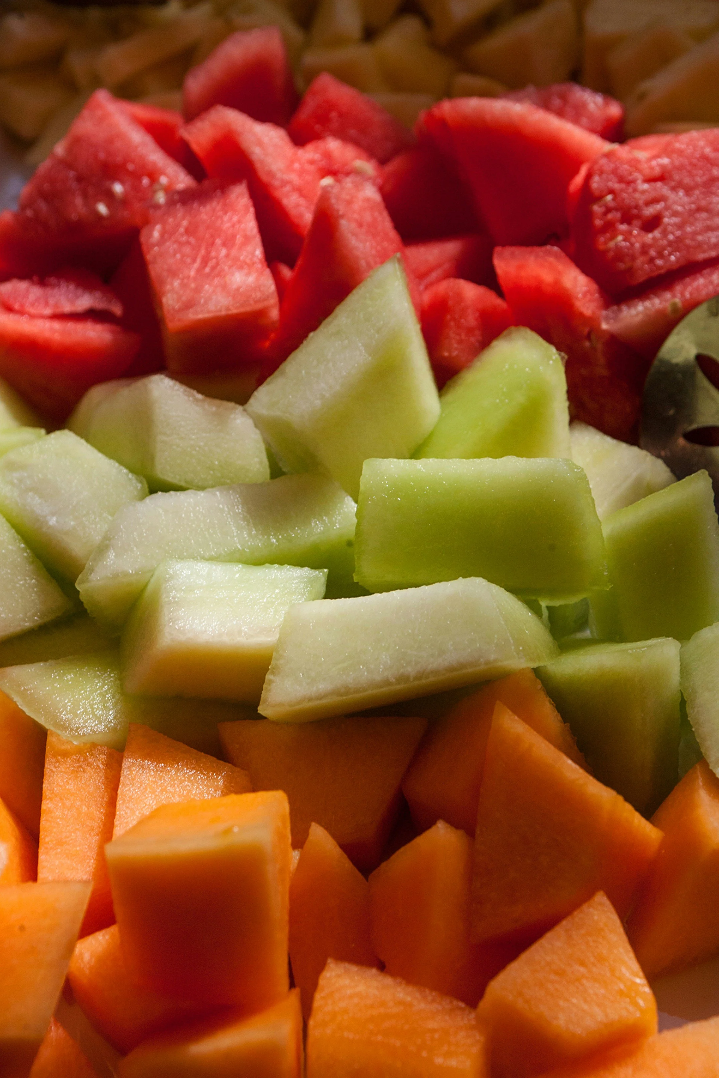 A close-up view of chopped watermelon, honeydew melon, cantaloupe, and pineapple in a mixed fruit salad.