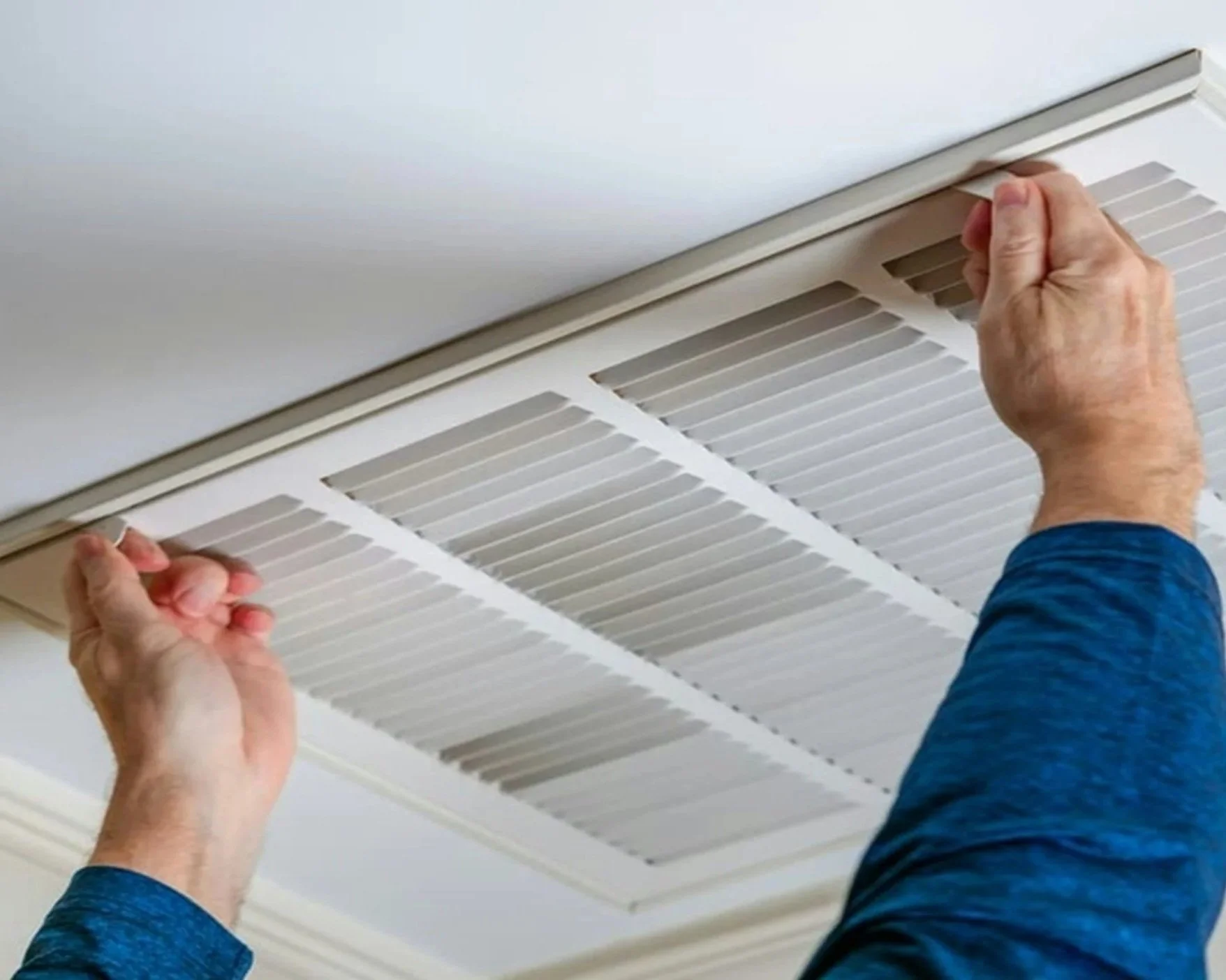 Handyman accessing air conditioning vent for filter replacement.