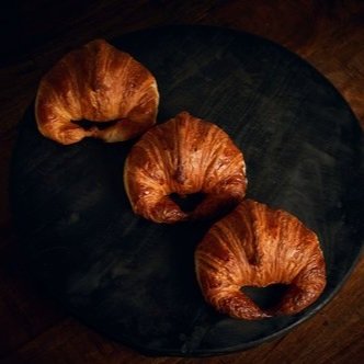Three croissants on a dark round table.
