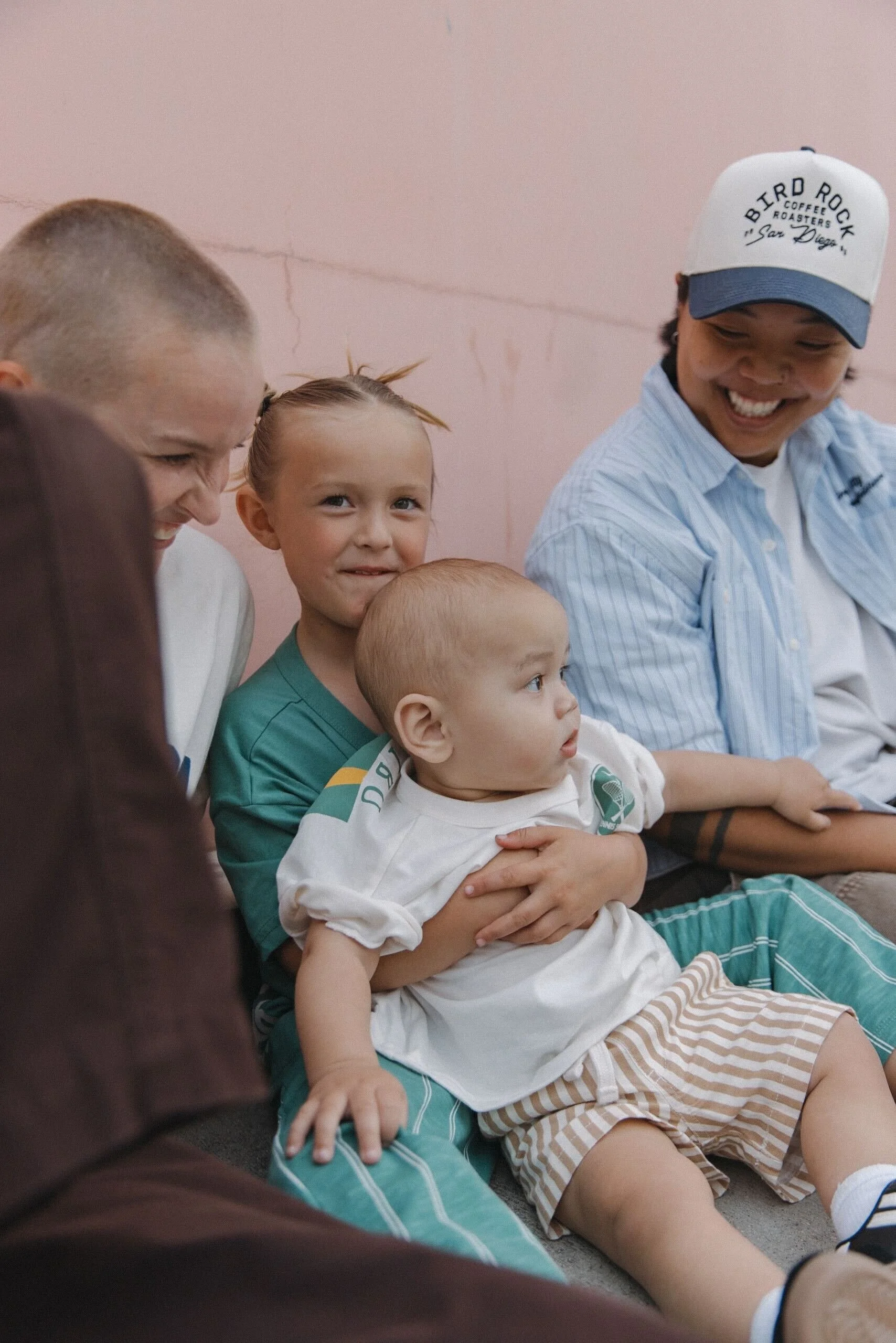 Group of children and young adults sitting together, smiling and engaging with each other.