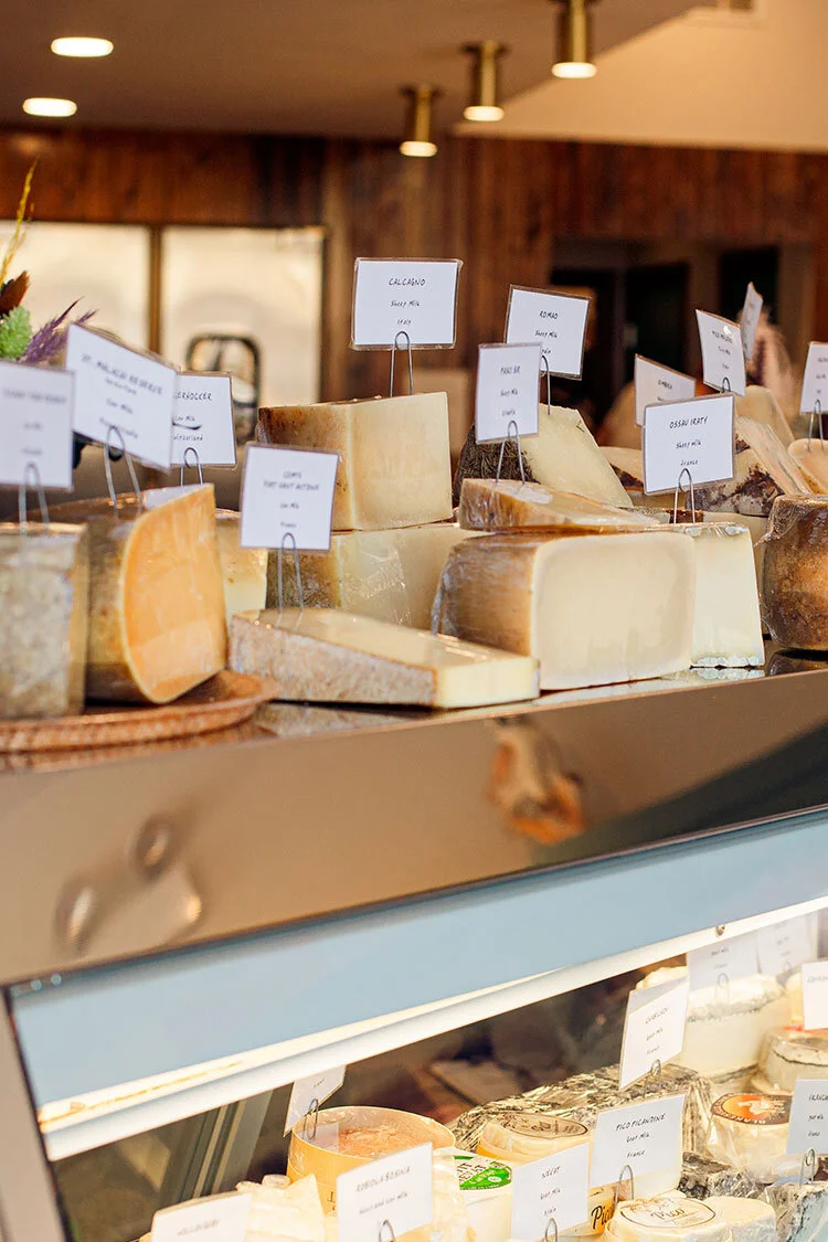 A cheese counter with a large variety of local and imported cheeses.