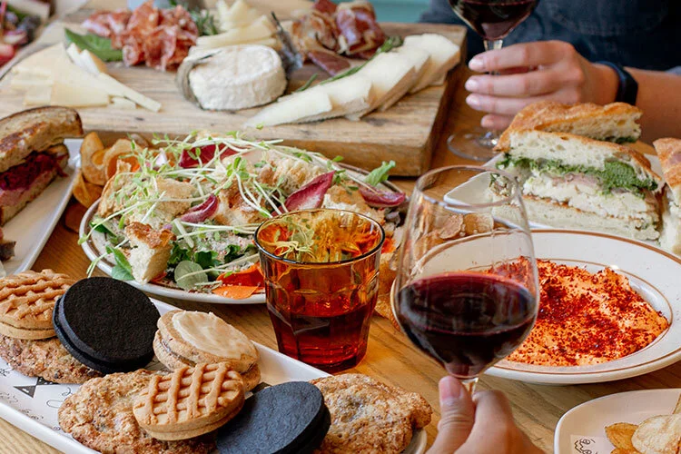 A table with of trays of desserts, cheese and charcuterie platters and salads for a corporate luncheon.
