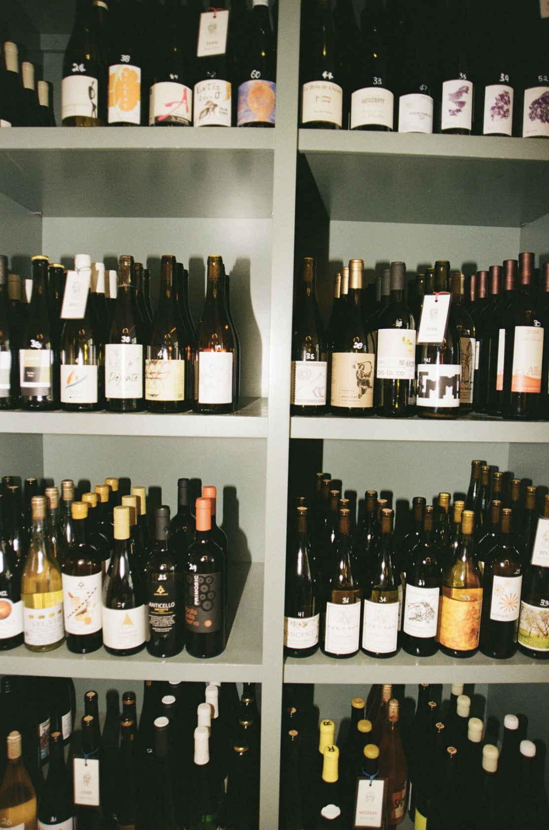 Shelves stocked with various bottles of natural wine, organized in three tiers.
