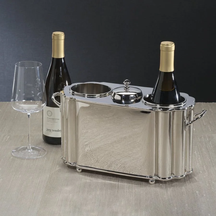 Luxury silver wine cooler with two bottles of wine, an empty wine glass, and wine accessories on a beige tablecloth against a dark background.