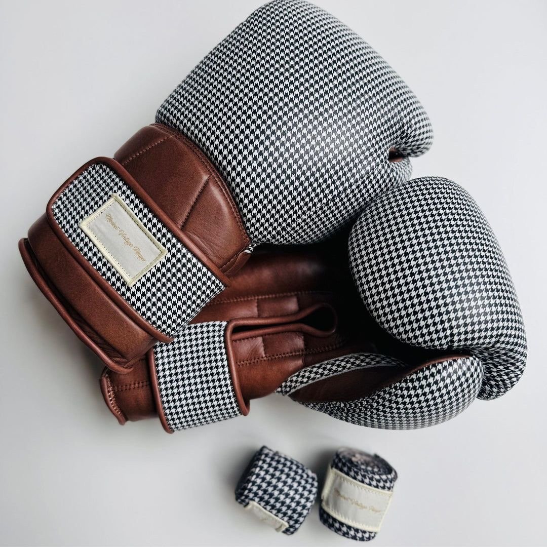 A set of houndstooth-patterned golf gloves and headcovers with brown leather accents, arranged on a white surface.