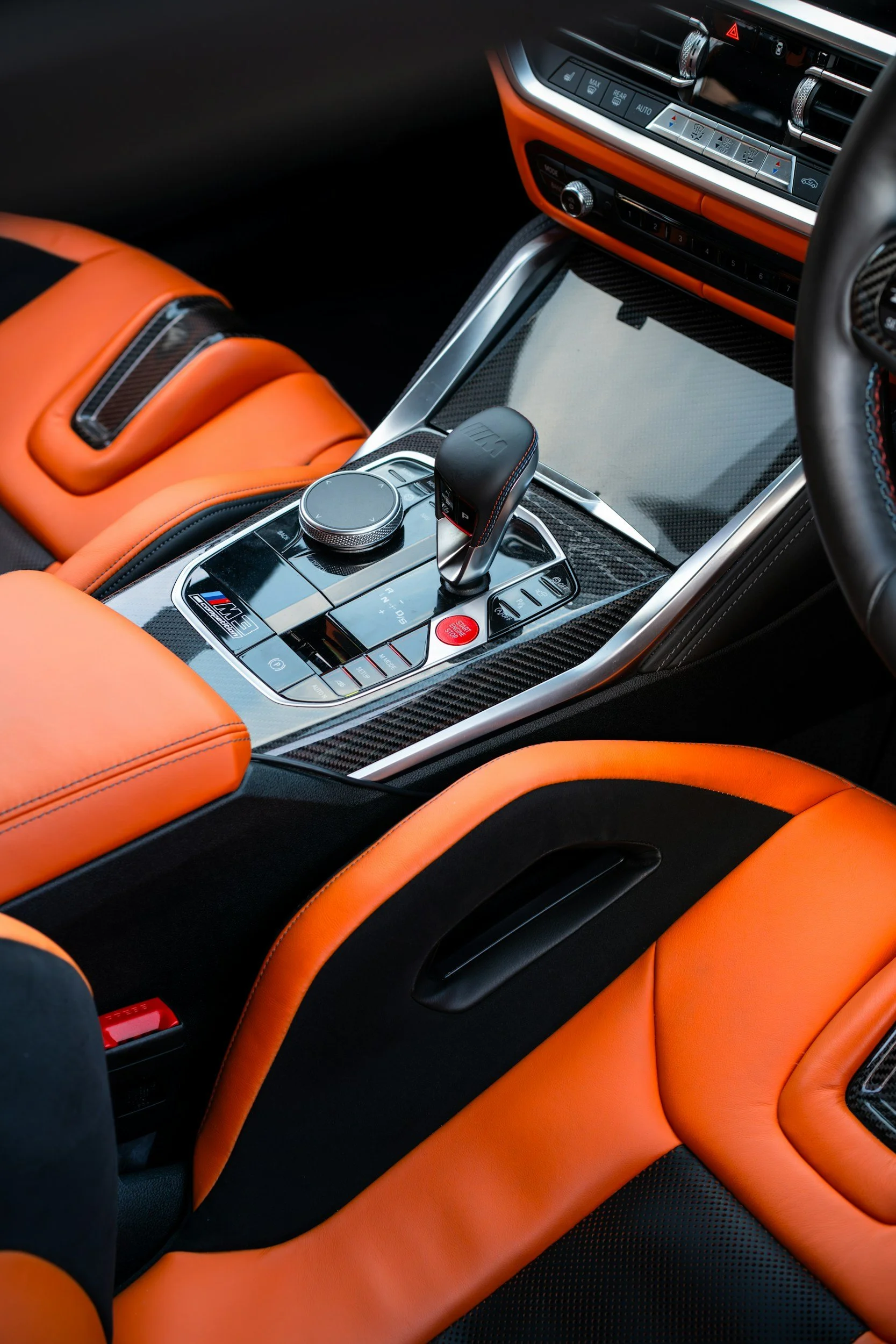 Interior of a luxury sports car with orange and black leather seats, a carbon fiber center console, and a modern gear shifter.
